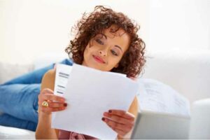 A lady looking at her A/C bills and smiling