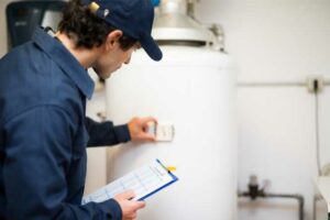 Plumber inspecting a hot water tank as part of annual plumbing maintenance