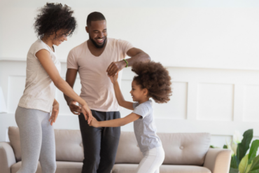 Happy biracial family with kid dancing at home