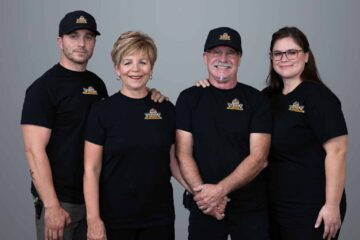 Vision Plumbing Heating Cooling's management team standing side-by-side wearing black t-shirts and hats with their new logo.