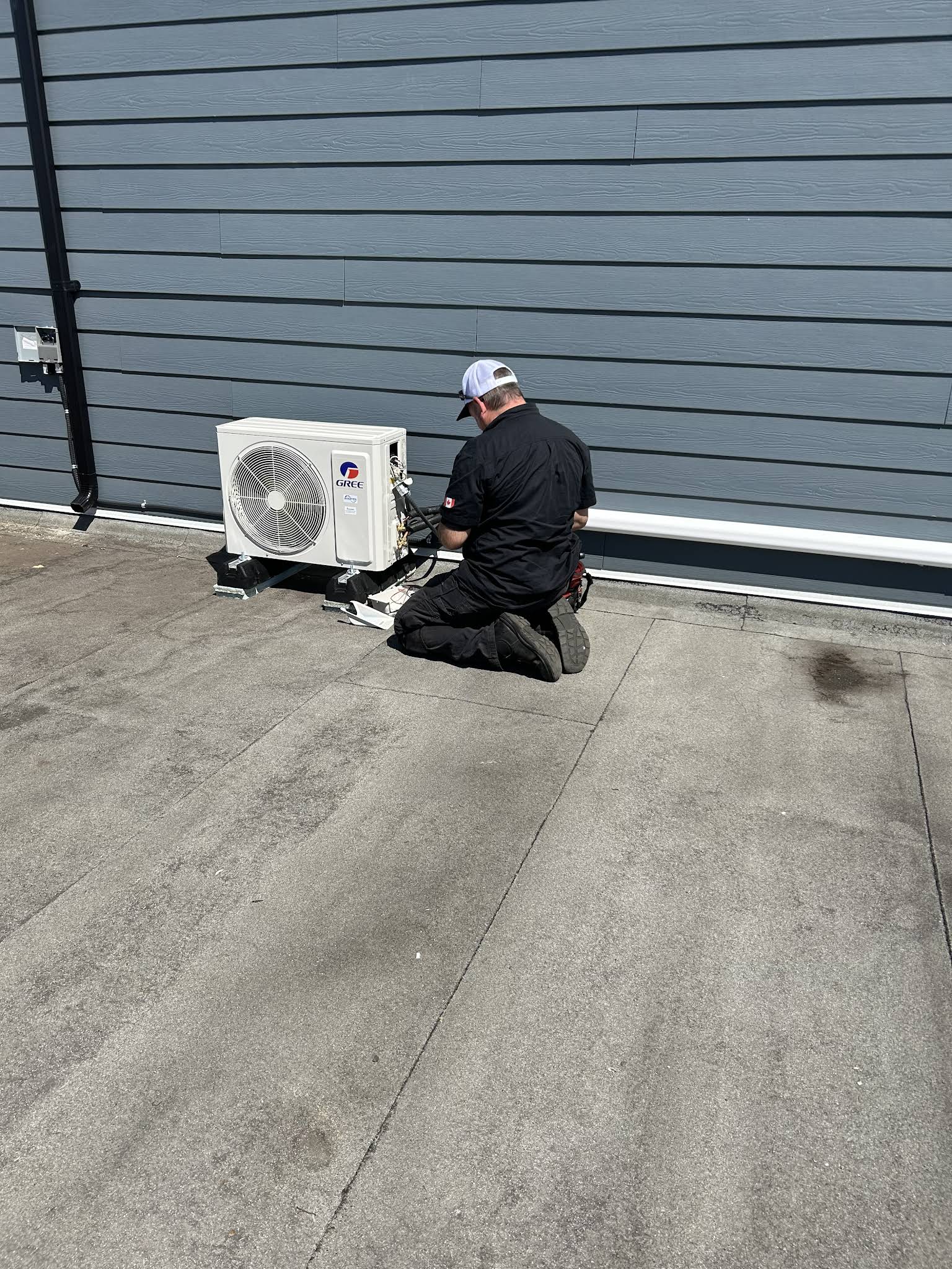 Vision Plumbing Heating Cooling HVAC tech working on a Heat Pump on a roof in Kelowna